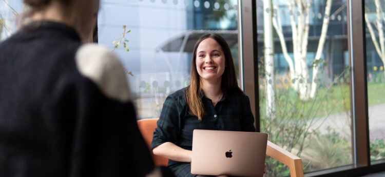 Two students facing each other smiling while sitting at a desk