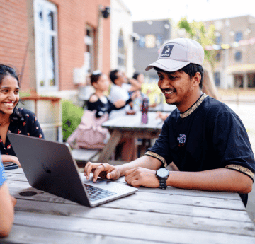 Student sitting outside on a desk using his computer.