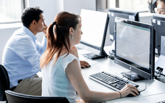 Two staff members working at a desk on their computers.