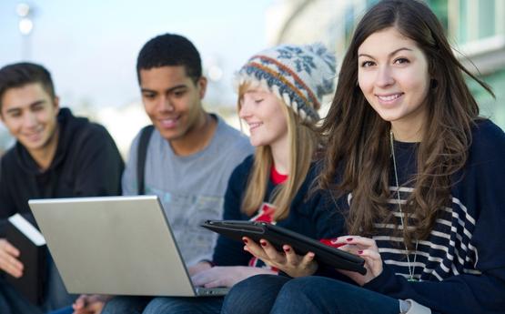 Group of students holding laptops and tablets