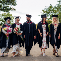 5 Students in Swansea university's cap and gown walking down the street at their graduation ceremony.