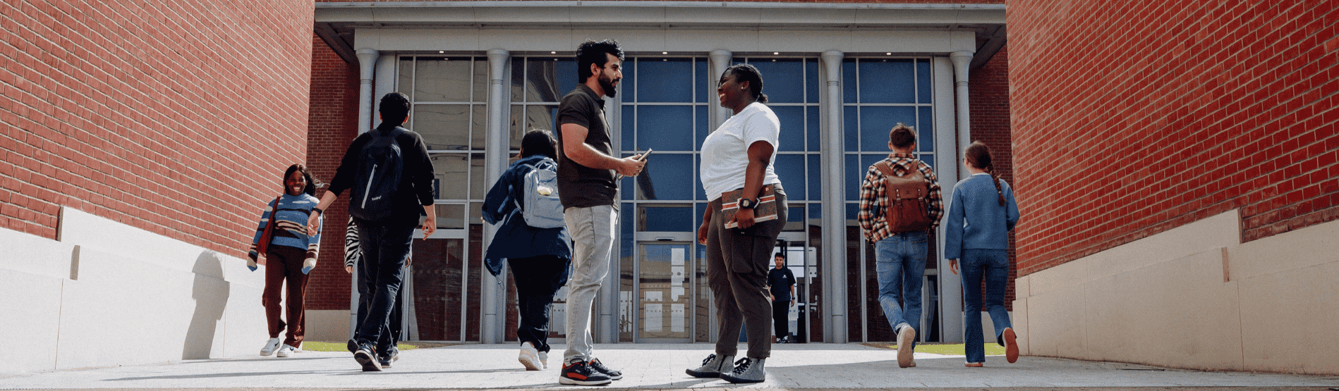 Two students talking to each other outside the Bay Campus library building