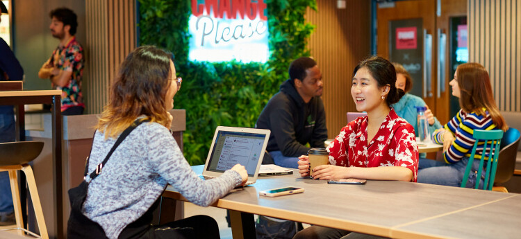 Students smiling while working together across a desk.