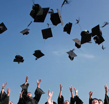 myfyrwyr yn taflu eu byrddau modur i'r awyr ar ôl graddio