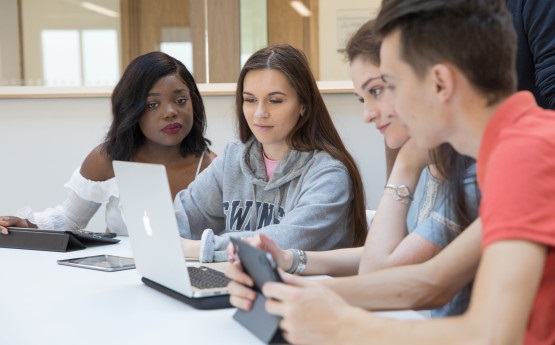 Three students working together around a laptop
