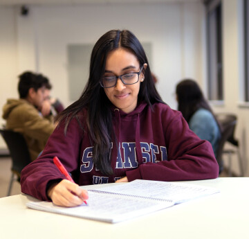 Student sitting and writing in the Library