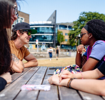 Students talking on a bench outside on Fulton House lawn